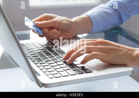 Donna mani tenendo la carta di credito e la digitazione sul portatile, il pagamento on-line su internet Foto Stock
