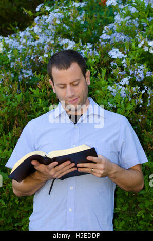 L'uomo della lettura della Bibbia all'aperto su una bella giornata. Foto Stock