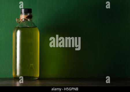 Olio d'oliva in bottiglia su sfondo verde Foto Stock