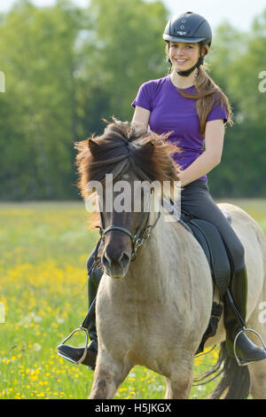Teen pilota sul retro di un islandese di equitazione in primavera Foto Stock
