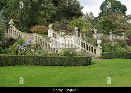 Un inglese formale giardino paesaggistico con scatola di copertura e di gradini di pietra e balaustra Foto Stock