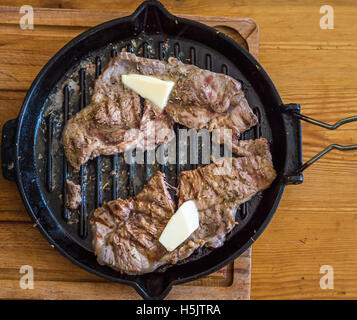 La carne fritta in una padella sulla tavola di legno Foto Stock