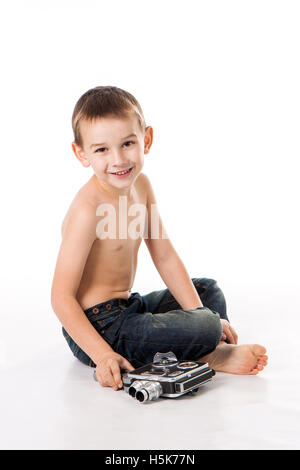 Ragazzo caucasico gioca a sparare alla vecchia macchina fotografica. Foto Stock