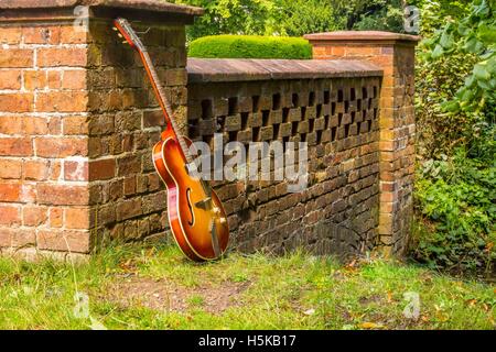 Un rosso e giallo di chitarra hofner appoggiata contro un ponte Foto Stock