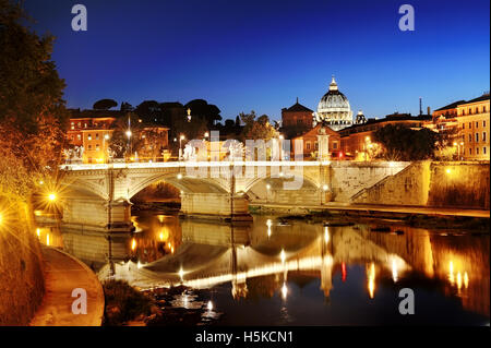 Roma, Italia - vista panoramica di un ponte sul fiume Tevere e sulla Basilica di San Pietro cupola in Vaticano durante la notte Foto Stock