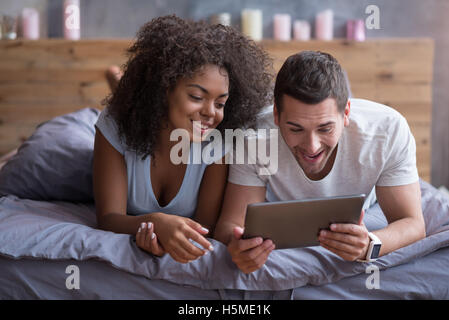 Primo piano giovane dolce coppia sul letto guardando qualcosa sul Tablet  Gadget, rilassarsi in camera da letto Foto stock - Alamy