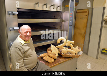 Sorridente baker holding pagnotta di pane Foto Stock