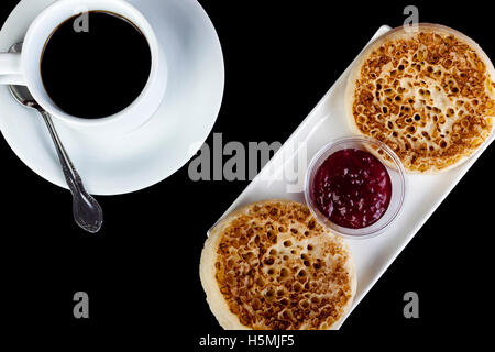 Cialdine fresco su un bianco rettangolare piatto con una tazza di caffè nero su sfondo nero Foto Stock