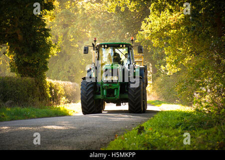 Un trattore John Deere che viaggiano lungo una strada di campagna Foto Stock