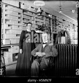 Questa fotografia del 1899 mostra due persone nel negozio di scarpe di George Burd situato in Main Street a Camden, Maine. L'immagine cattura un momento di vita lavorativa a Camden, con uno dei soggetti potenzialmente George Burd, il proprietario del negozio. Foto Stock