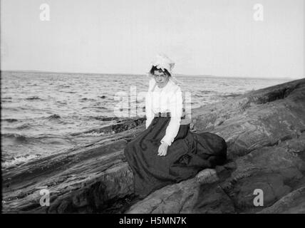 Emmie Fountain è seduta sulle sporgenze di Ogier Point a Camden, Maine, in una fotografia scattata nel 1900. La scena cattura il pittoresco porto di Camden, riflettendo la vita nel Maine durante quell'epoca. Foto Stock