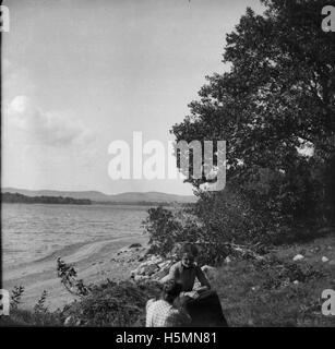 Due donne seduti vicino alla spiaggia sul lago Megunticook nel settembre 1900. Foto Stock