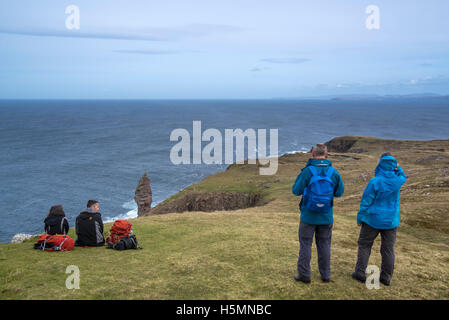 Walkers adagiata vicino il vecchio uomo di Stoer, alta 60 metri mare pila in corrispondenza del punto di Stoer, Sutherland, Highlands scozzesi, Scozia Foto Stock