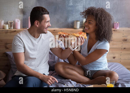 Gioiosa giovane alimentazione di ogni altro con una gustosa pizza. Foto Stock