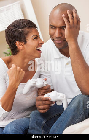 African American giovane, uomo e donna, divertendosi console video games insieme. La donna ha appena battuto l'uomo, lei Foto Stock