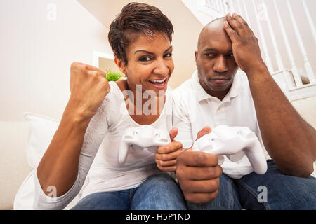 African American giovane, uomo e donna, divertendosi console video games insieme. La donna ha appena battuto l'uomo, lei Foto Stock