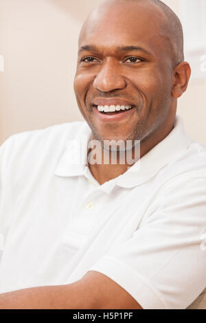 Un felice bello African American uomo con denti perfetti nei suoi trent'anni seduti a casa Foto Stock