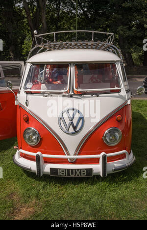 Un rosso e bianco a schermo diviso VW camper van in mostra a Paignton verde con alberi in background Foto Stock