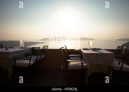 Un ristorante con tavoli che si affaccia sul mare e sulle isole del tramonto. Foto Stock