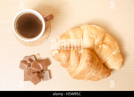 Due cornetti al forno con una tazza di caffè e cioccolato. Foto Stock