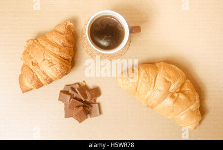 Due cornetti al forno con una tazza di caffè e cioccolato. Foto Stock