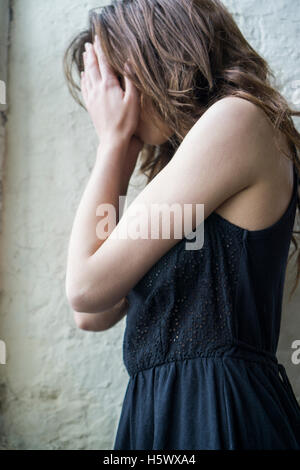 Giovane donna nasconde il viso con le mani Foto Stock