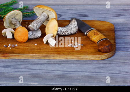 I funghi selvatici e di un coltello che giace sulla vecchia quercia scheda di taglio. Foto Stock