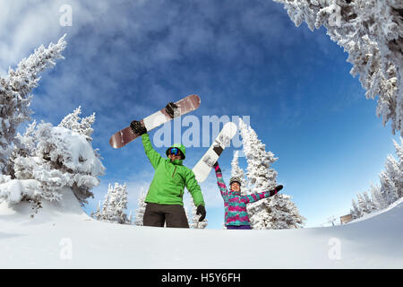 Gli appassionati di snowboard in posa sul cielo blu sullo sfondo di montagne Foto Stock