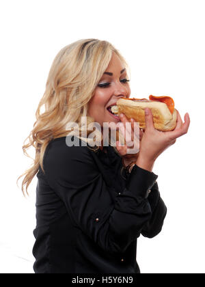 Un attraente donna bionda sta mangiando un stile deli sandwich. Foto Stock