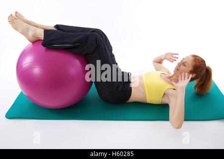 Donna esercizio con una fitball su un tappeto di ginnastica Foto Stock