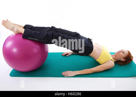 Donna esercizio con una fitball su un tappeto di ginnastica Foto Stock