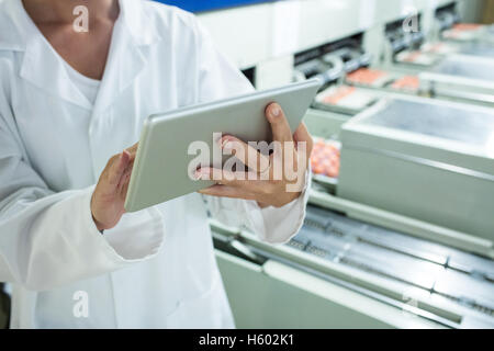 La sezione centrale del personale femminile con tavoletta digitale accanto alla linea di produzione Foto Stock