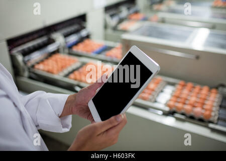 La sezione centrale del personale femminile con tavoletta digitale accanto alla linea di produzione Foto Stock