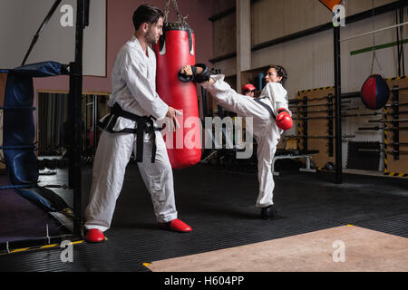 L uomo e la donna a praticare il karate con sacco da boxe Foto Stock