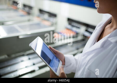 La sezione centrale del personale femminile con tavoletta digitale accanto alla linea di produzione Foto Stock