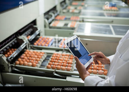 La sezione centrale del personale femminile con tavoletta digitale accanto alla linea di produzione Foto Stock