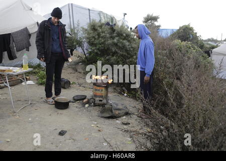 Calais, UK. Xxi oct, 2016. I rifugiati stand attorno a un fuoco aperto davanti alle loro tende. Giorno per giorno la vita nella giungla continua con pochi giorni per andare per lo sfratto di camp da parte dello Stato francese. Tuttavia più e più persone stanno lasciando il campo e il numero di vuota tende e capanne aumenta. Credito: Michael Debets/Pacific Press/Alamy Live News Foto Stock