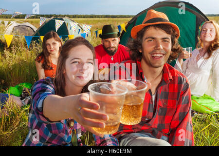 Felice giovani amici cembalo che bicchieri al campeggio Foto Stock