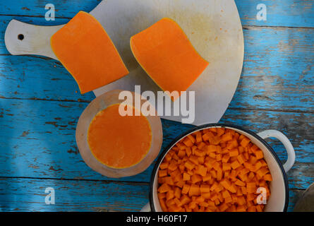 Tagliato in sezioni e pezzi di colore arancione brillante zucca è su sfondo bianco del carving board sulla tabella delle tavole di legno Foto Stock