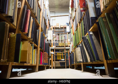 Molto vecchia libreria in cattive condizioni. I libri sugli scaffali. Scaletta sul retro della libreria. Foto Stock