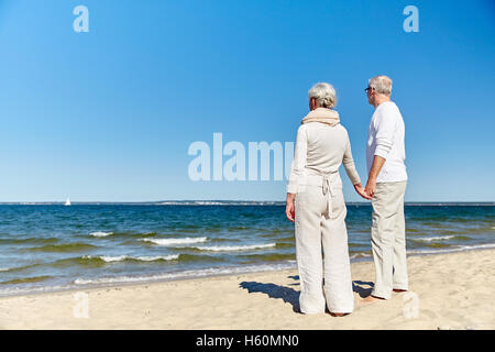 Felice coppia senior holding hands estate spiaggia Foto Stock