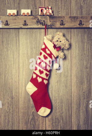 Calza di Natale riempito con Teddy bear e treno impostato sulla mensola Foto Stock