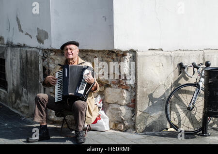 Un uomo anziano busks con la sua accodion sulle strade di Budapest. Foto Stock