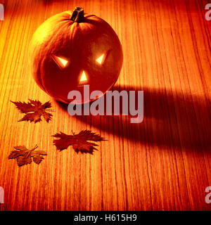Elegante Decorazione Halloween, zucca intagliata con faccia paura e a lume di candela, albero secco foglie su un tavolo di legno Foto Stock