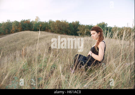 Donna incinta in abito nero e dreadlocks sullo sfondo di una natura selvaggia Foto Stock