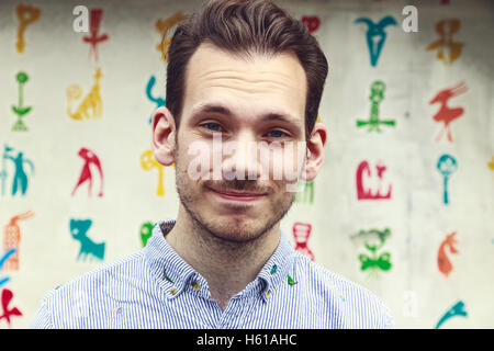Ritratto di accettare un giovane uomo in piedi contro un colorato sfondo funky Foto Stock