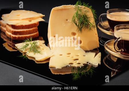 Formaggio con finocchio, pane bianco e due tazze di caffè su sfondo nero Foto Stock