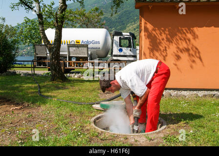 Melano, Svizzera -20 Maggio 2005: lavoratore rendendo la fornitura di gas su di un serbatoio nel giardino di una casa a Melano sulla Svizzera Foto Stock