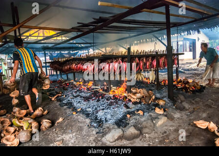 I lavoratori stanno mantenendo la distribuzione di buccia di cocco bruciando che ha usato come combustibile per fumare le carni di tonno di skipjack a Bitung, Sulawesi del nord, Indonesia. Foto Stock