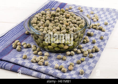 Piselli secchi in una ciotola di vetro con acqua fredda e alcuni su un asciugamano da cucina Foto Stock